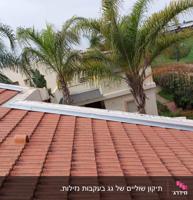 גג רעפים אדומים עם תעלה מתכתית לאורכו